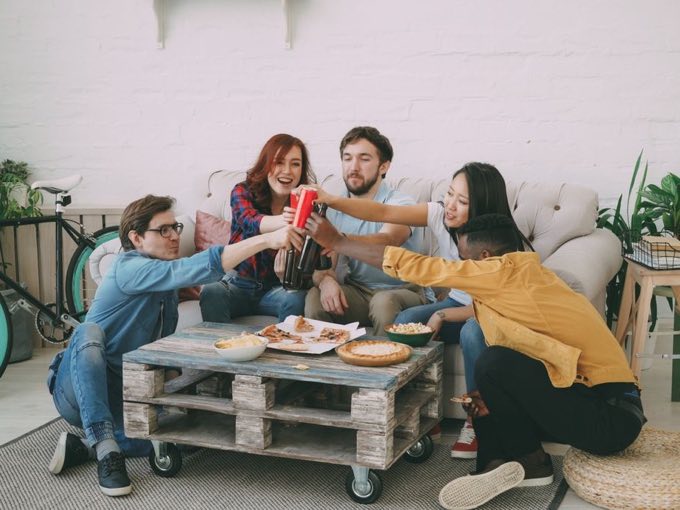 Friends toasting over pizza in a living room